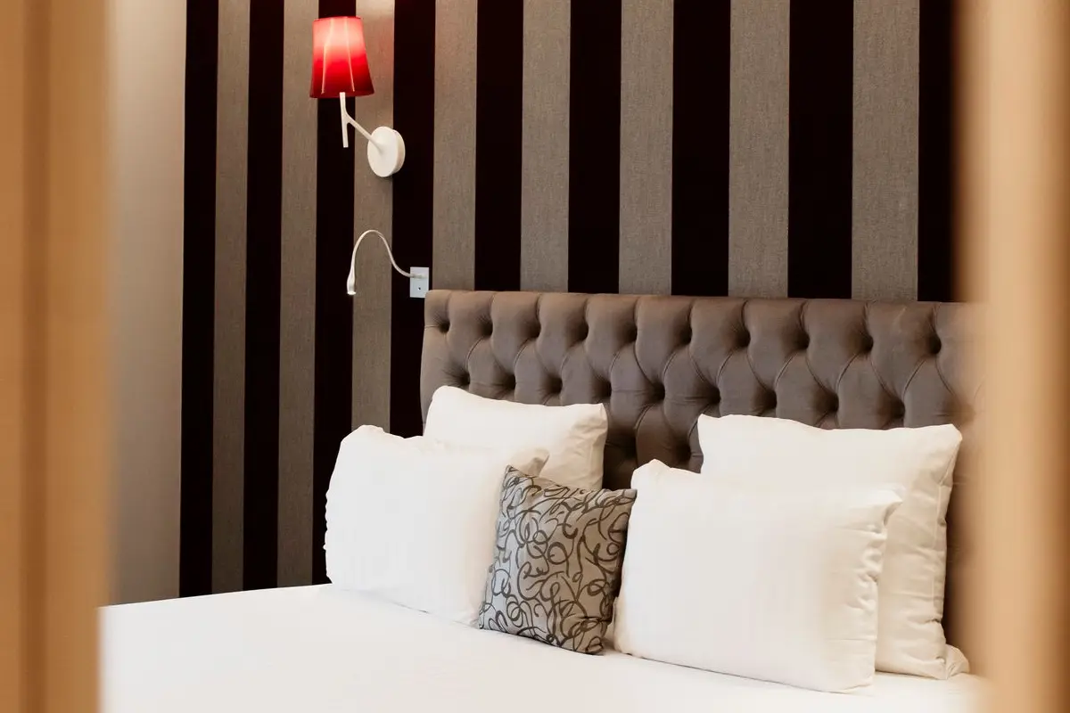 Tête de lit capitonnée et éclairage mural dans une chambre élégante de l’Hôtel Dali Val d’Europe