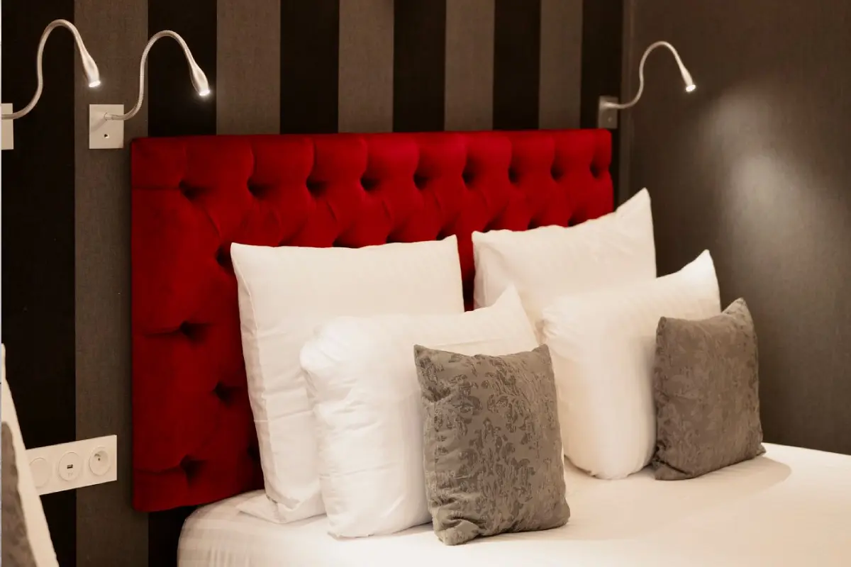 Chambre de l’Hôtel Dali Val d’Europe avec tête de lit rouge capitonnée et oreillers décoratifs